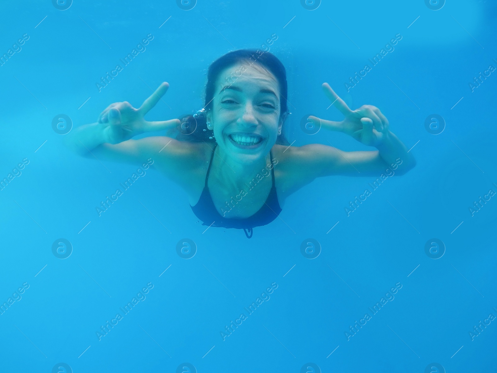 Photo of Beautiful young woman swimming in pool, underwater view