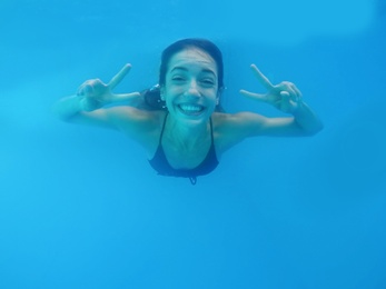 Beautiful young woman swimming in pool, underwater view