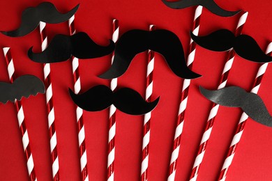 Photo of Fake paper mustaches with party props on red background, flat lay