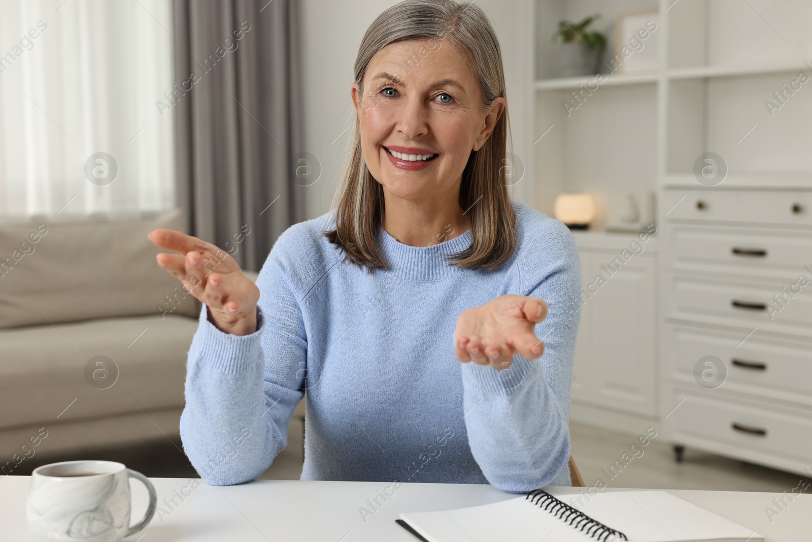 Photo of Happy woman at white table in room