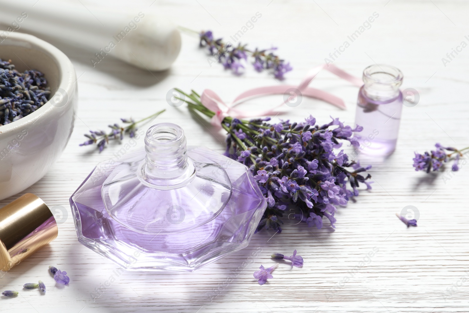 Photo of Bottle of natural perfume and lavender flowers on white wooden table. Cosmetic product