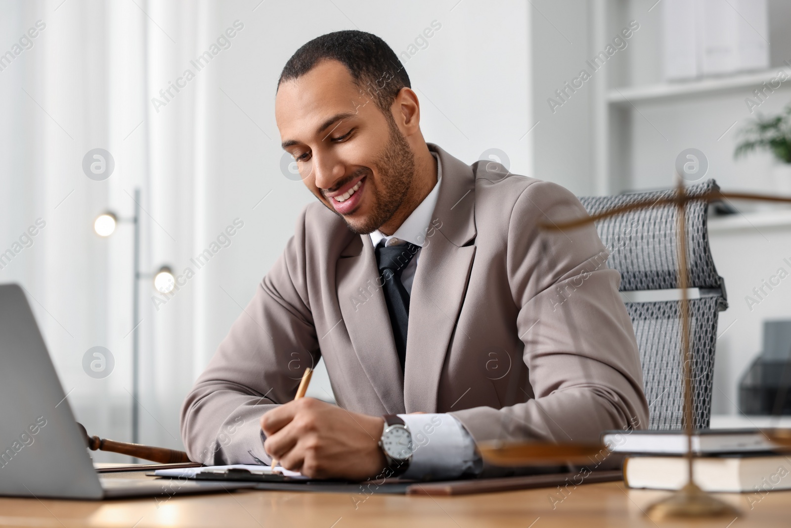 Photo of Smiling lawyer working at table in office