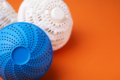 Photo of Laundry dryer balls on orange background, closeup. Space for text