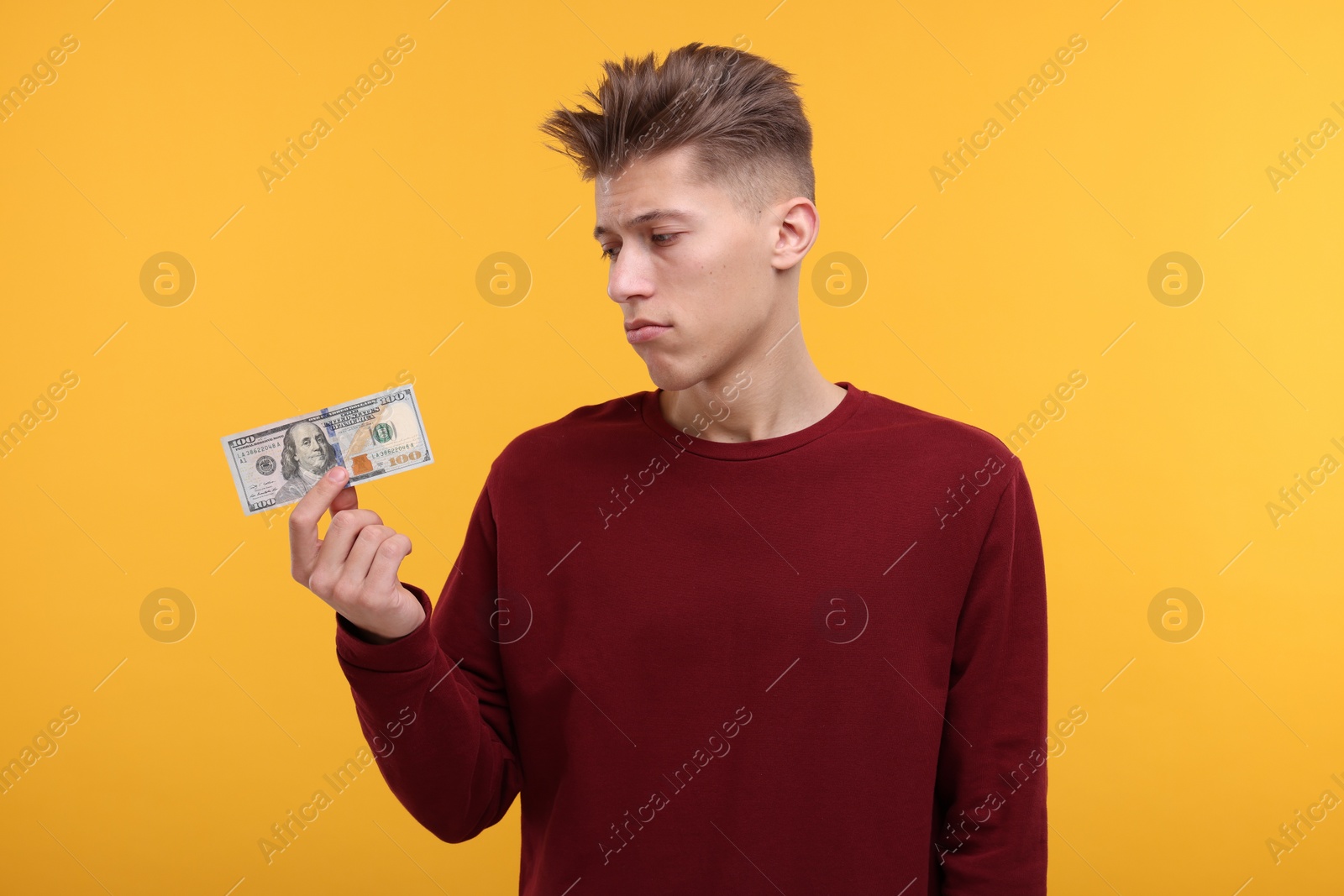 Photo of Upset man with dollar banknote on yellow background