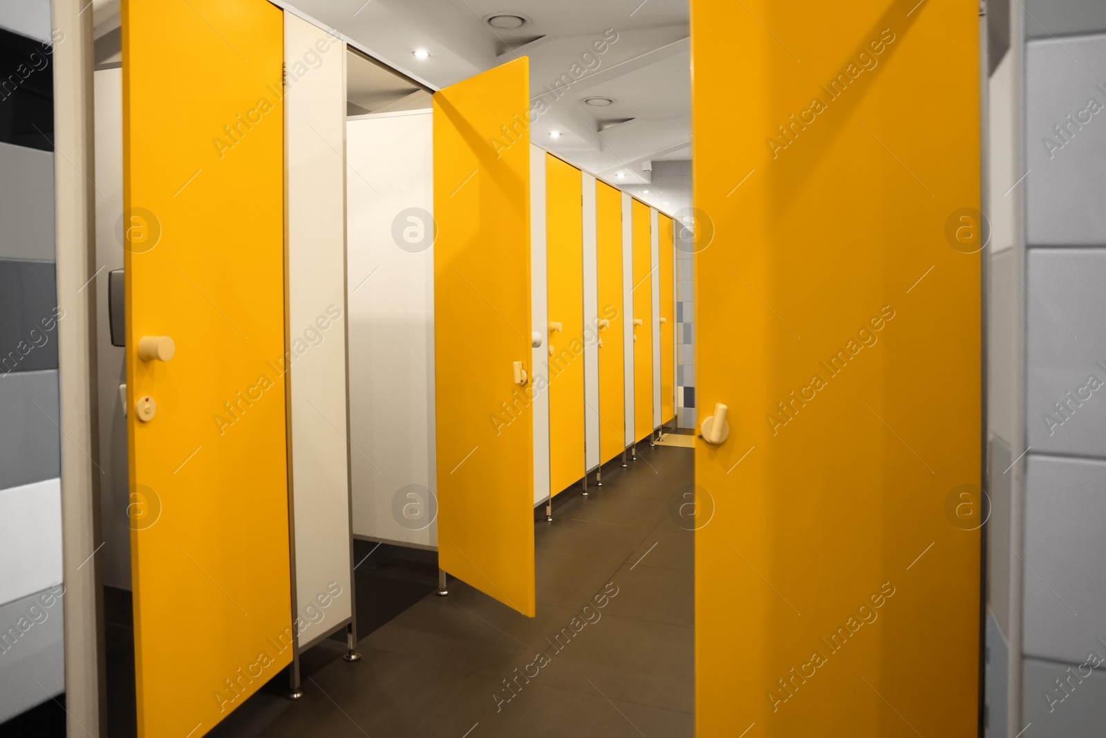 Photo of Public toilet interior with bright yellow stalls