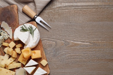Photo of Cheese plate on wooden table, top view. Space for text