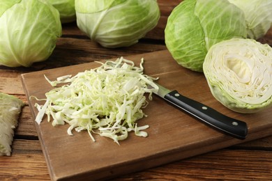 Photo of Chopped ripe cabbage and knife on wooden board, closeup