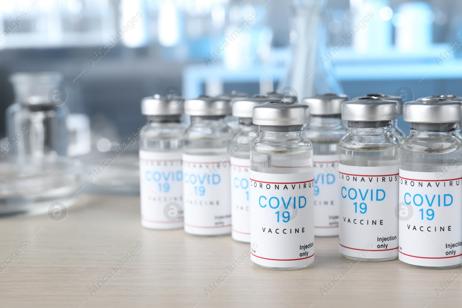 Photo of Glass vials with COVID-19 vaccine on wooden table. Space for text