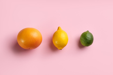 Grapefruit, lemon and lime on pink background, flat lay