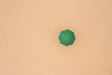 Image of Green beach umbrella on sandy coast, aerial view. Space for text