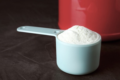 Photo of Scoop of protein powder on grey stone table