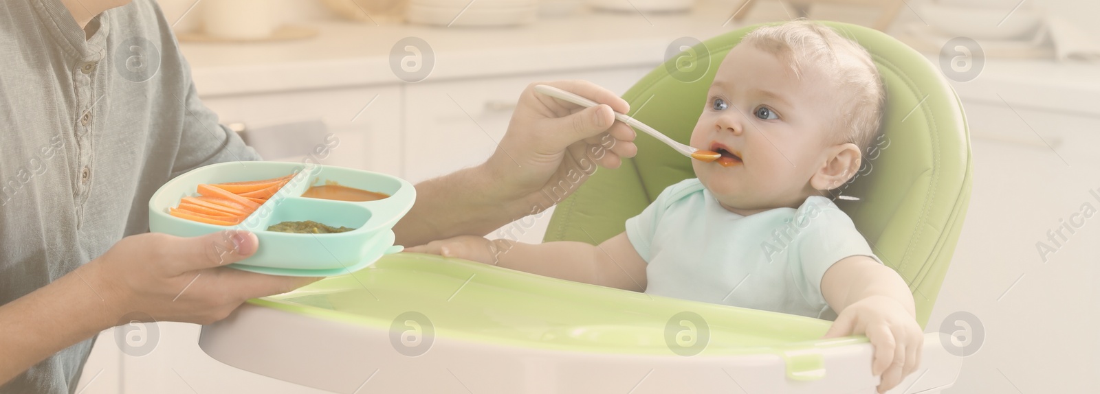 Image of Father feeding his cute little baby in kitchen. Banner design