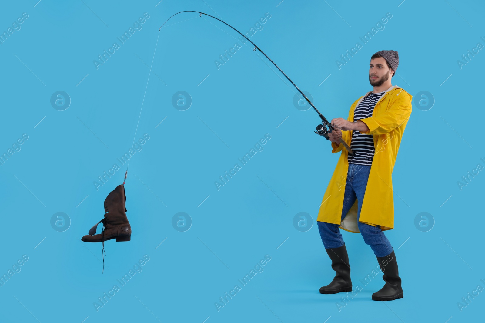 Photo of Fisherman with rod and old boot on light blue background