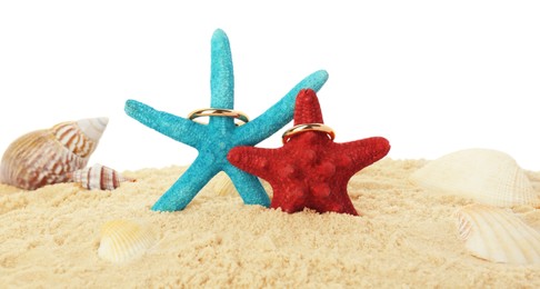 Photo of Honeymoon concept. Two golden rings, sea stars, seashells and sand isolated on white