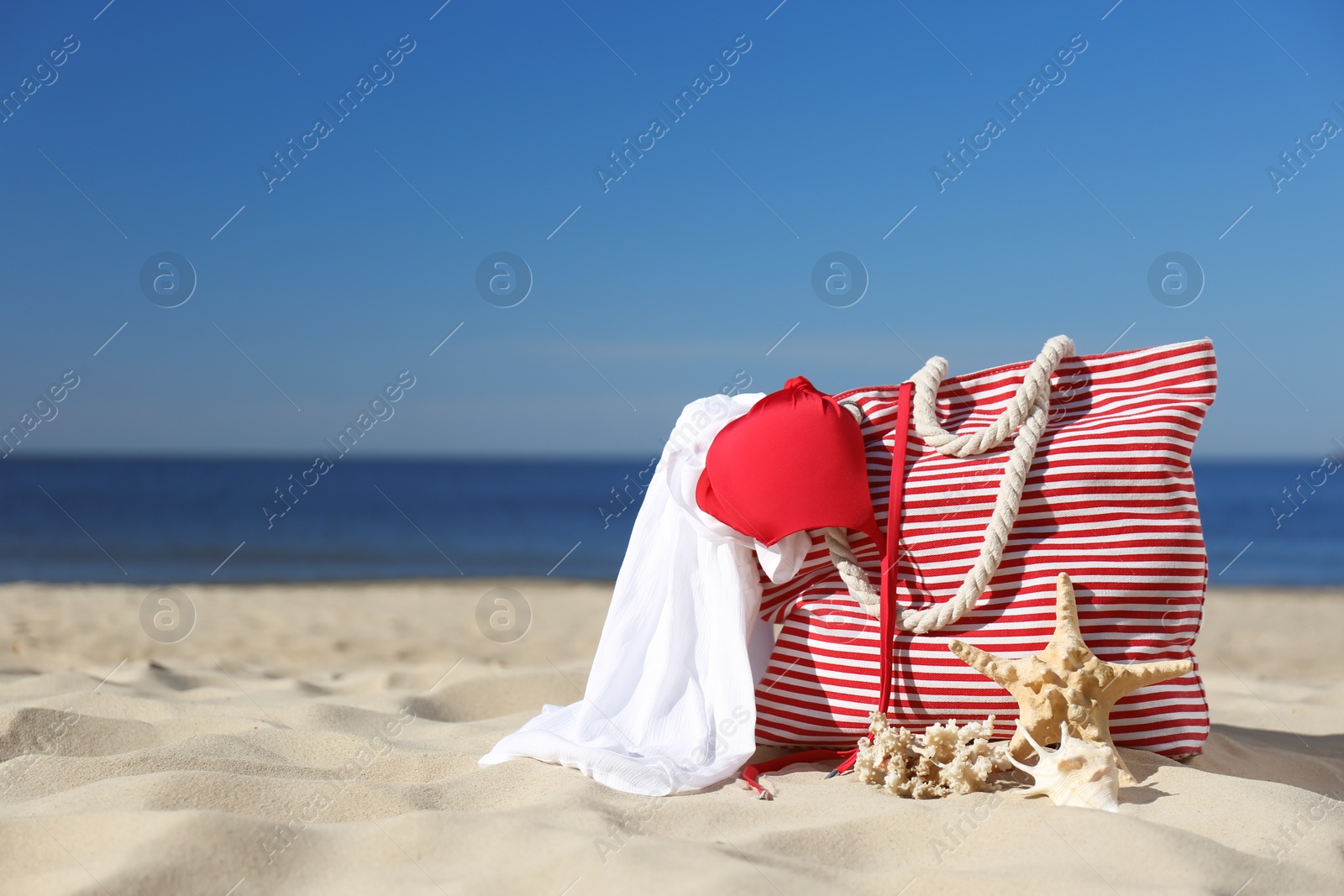 Photo of Stylish beach accessories for summer vacation on sand near sea. Space for text