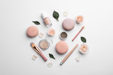 Photo of Flat lay composition with makeup products, roses and macarons on white background