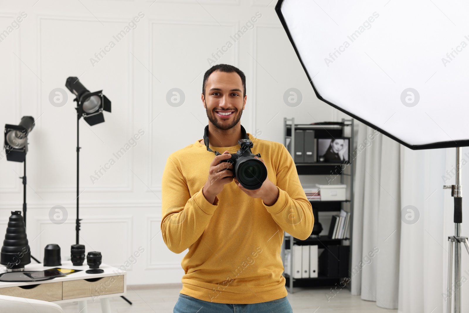 Photo of Young professional photographer with camera in modern photo studio