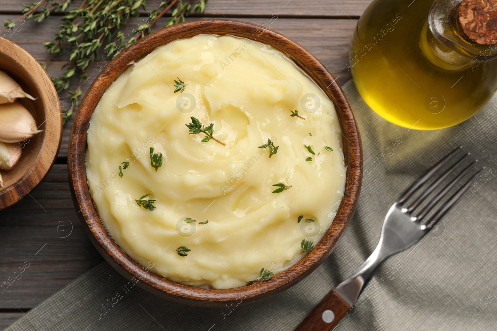 Photo of Delicious mashed potato with thyme served on wooden table, flat lay