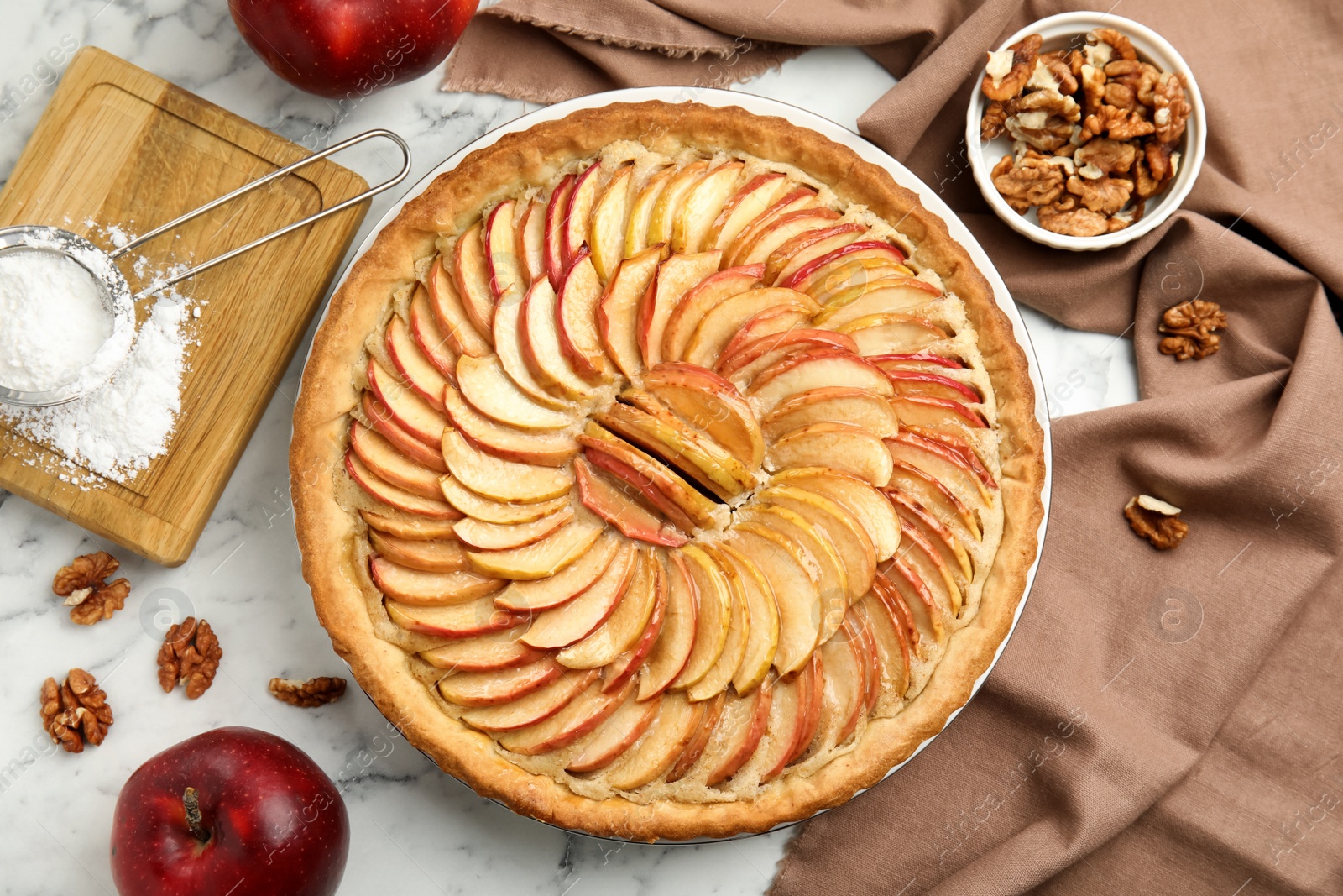 Photo of Delicious homemade apple tart and ingredients on white marble table, flat lay