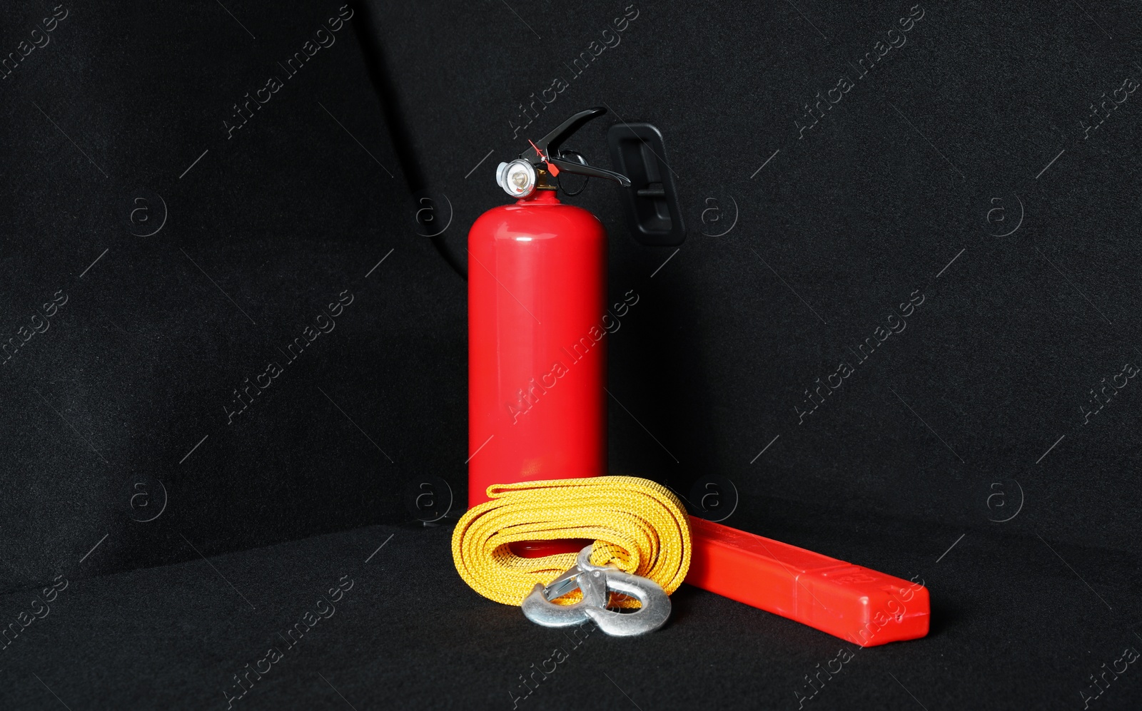 Photo of Red fire extinguisher, towing strap and foldable emergency warning triangle in trunk. Car safety