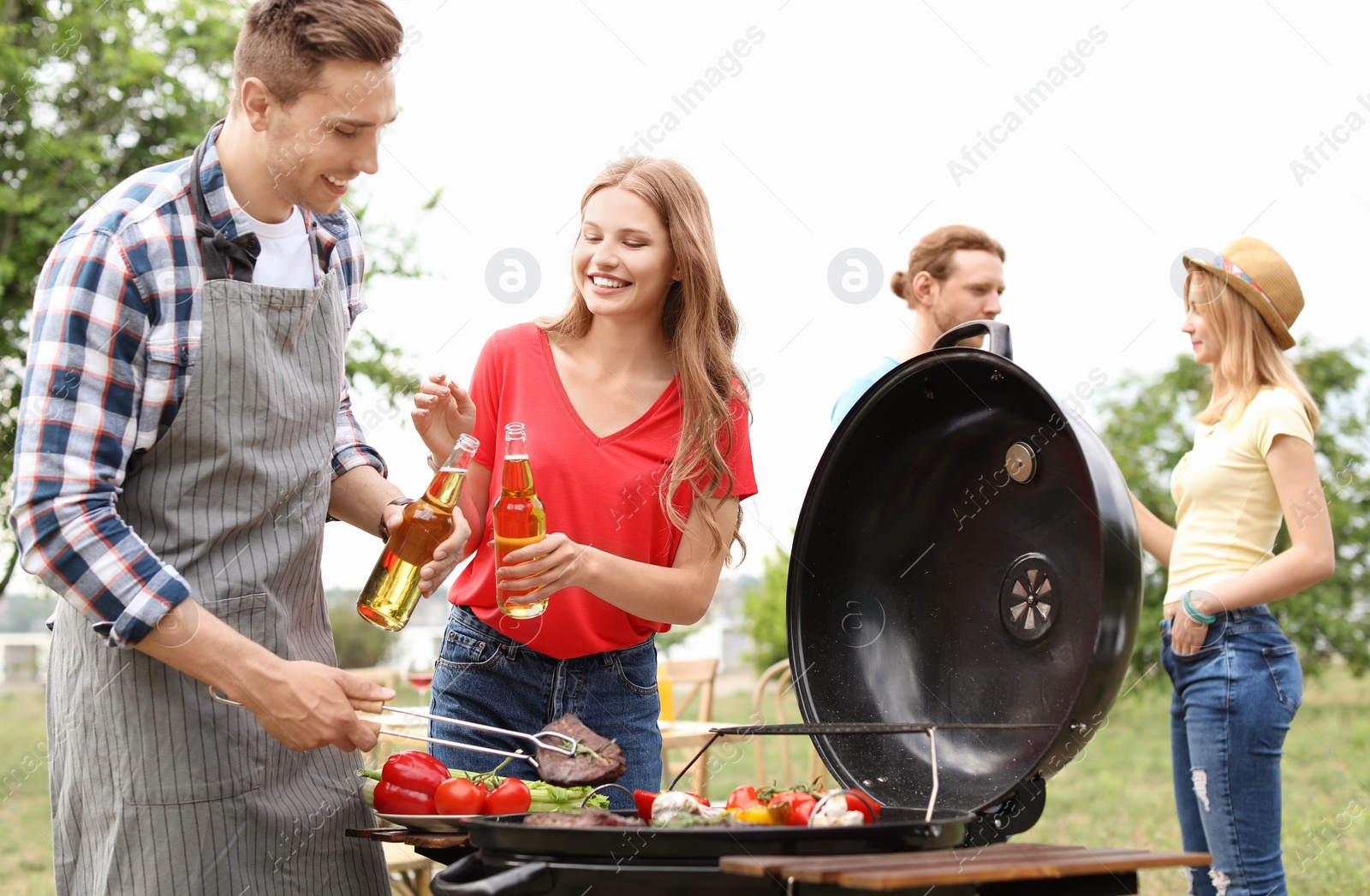 Photo of Young people having barbecue with modern grill outdoors