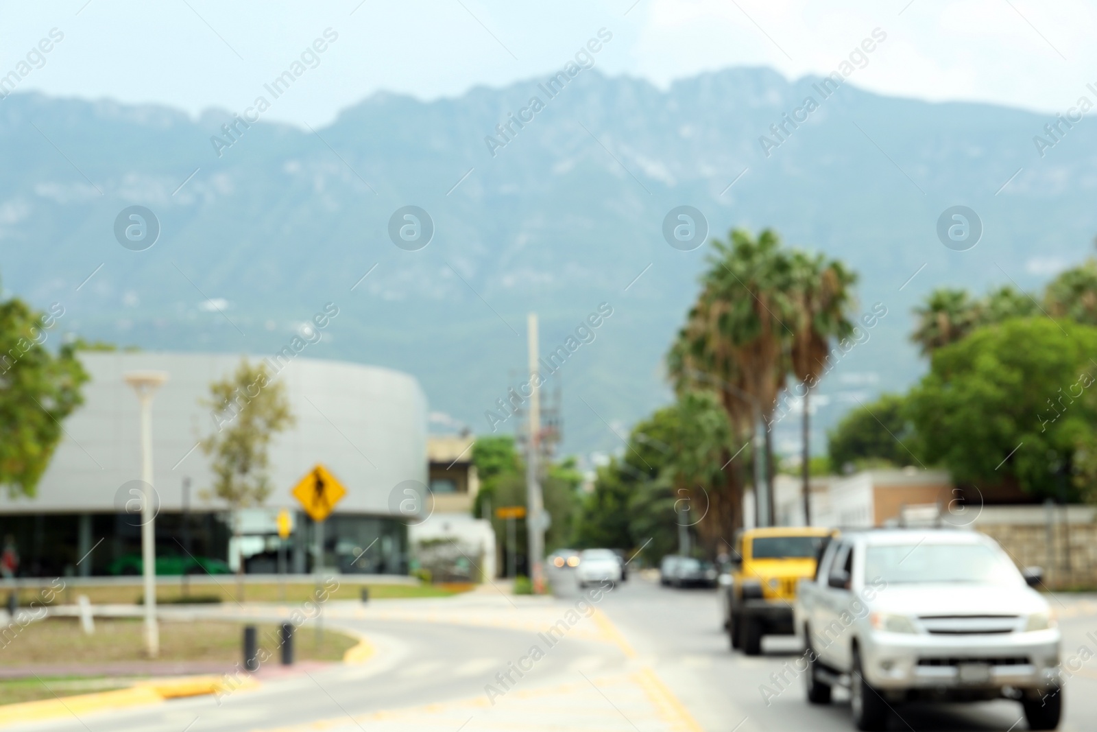 Photo of Asphalt road with modern cars near mountains, blurred view