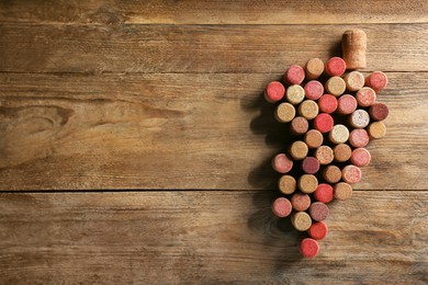 Photo of Grape made of wine bottle corks on wooden table, top view. Space for text