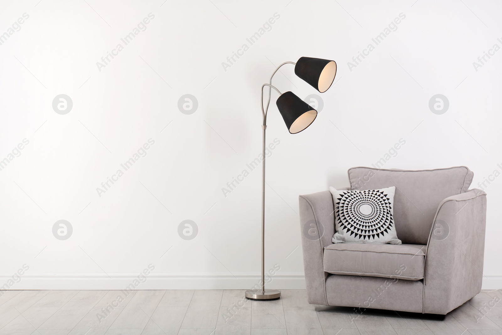 Photo of Comfortable armchair and lamp near wall with space for design. Stylish interior elements