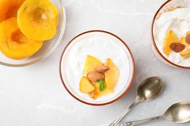 Photo of Tasty peach dessert with yogurt served on light table, flat lay