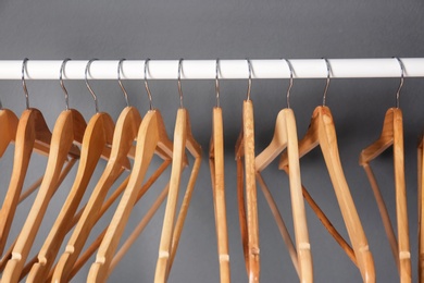 Photo of Clothes rail with wooden hangers on gray background