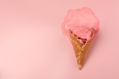 Photo of Melted ice cream in wafer cone on pink background, top view. Space for text