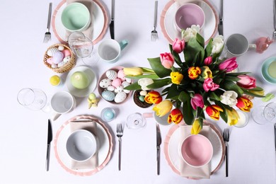 Festive table setting with beautiful flowers, flat lay. Easter celebration