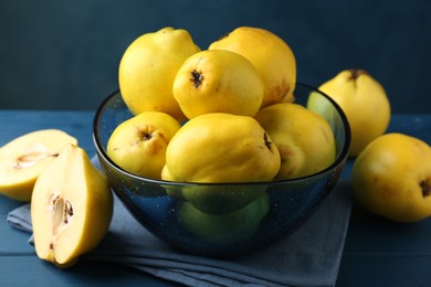 Tasty ripe quinces in bowl on blue wooden table, closeup