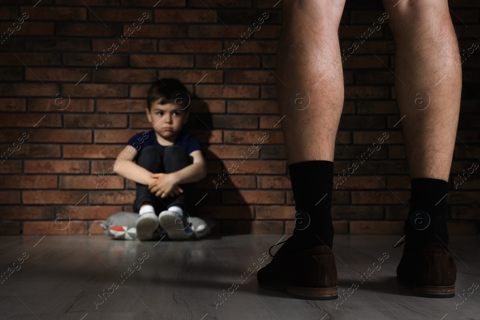 Photo of Adult man without pants standing in front of despaired little boy indoors. Child in danger