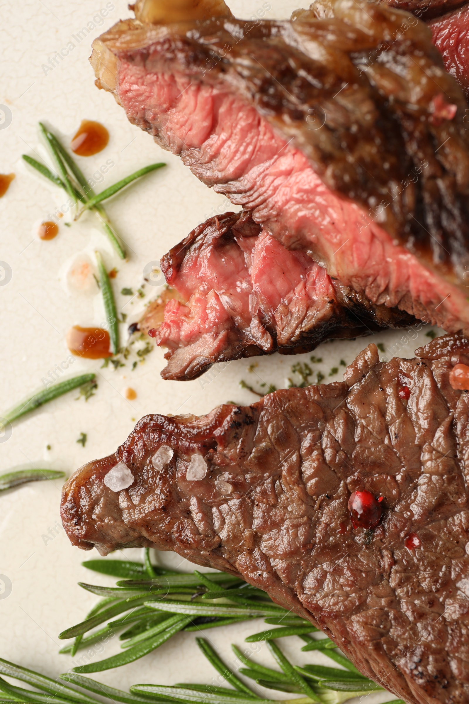 Photo of Delicious grilled beef steak and rosemary on plate, top view