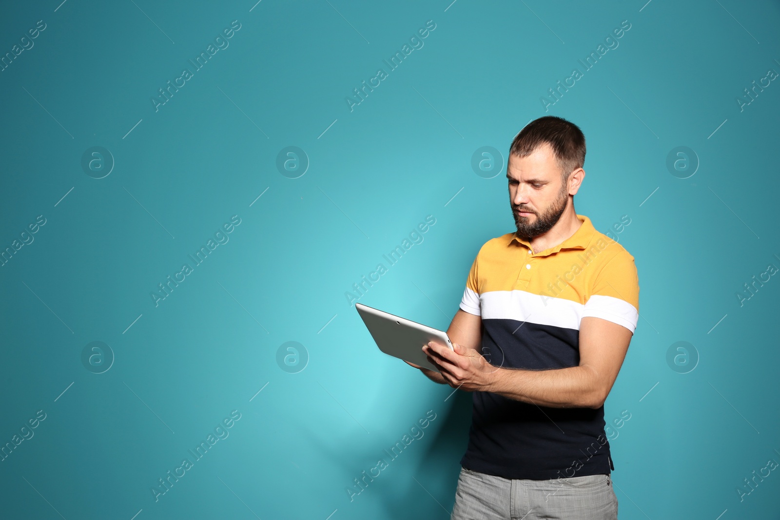 Photo of Man in casual clothes with tablet on color background