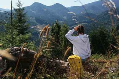 Tourist enjoying mountain landscape near backpack outdoors on sunny day, back view