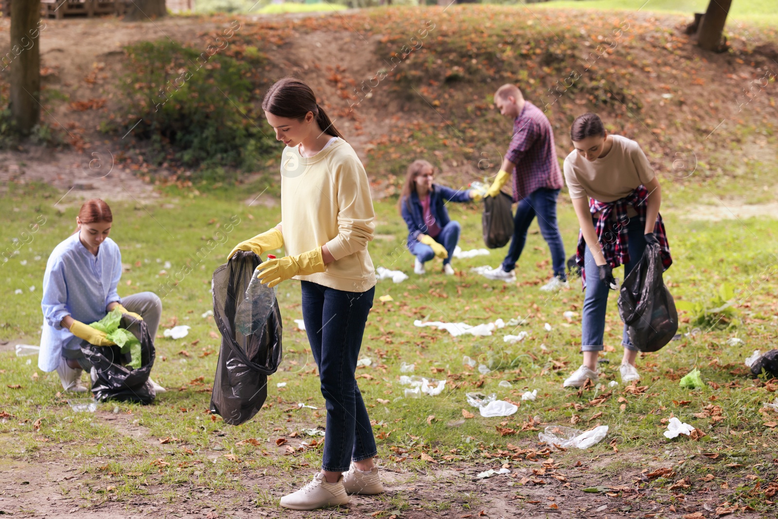 Photo of Group of people with plastic bags collecting garbage in park