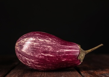 Photo of Ripe purple eggplant on wooden table, closeup