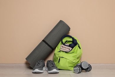 Photo of Backpack and sports equipment on floor near beige wall