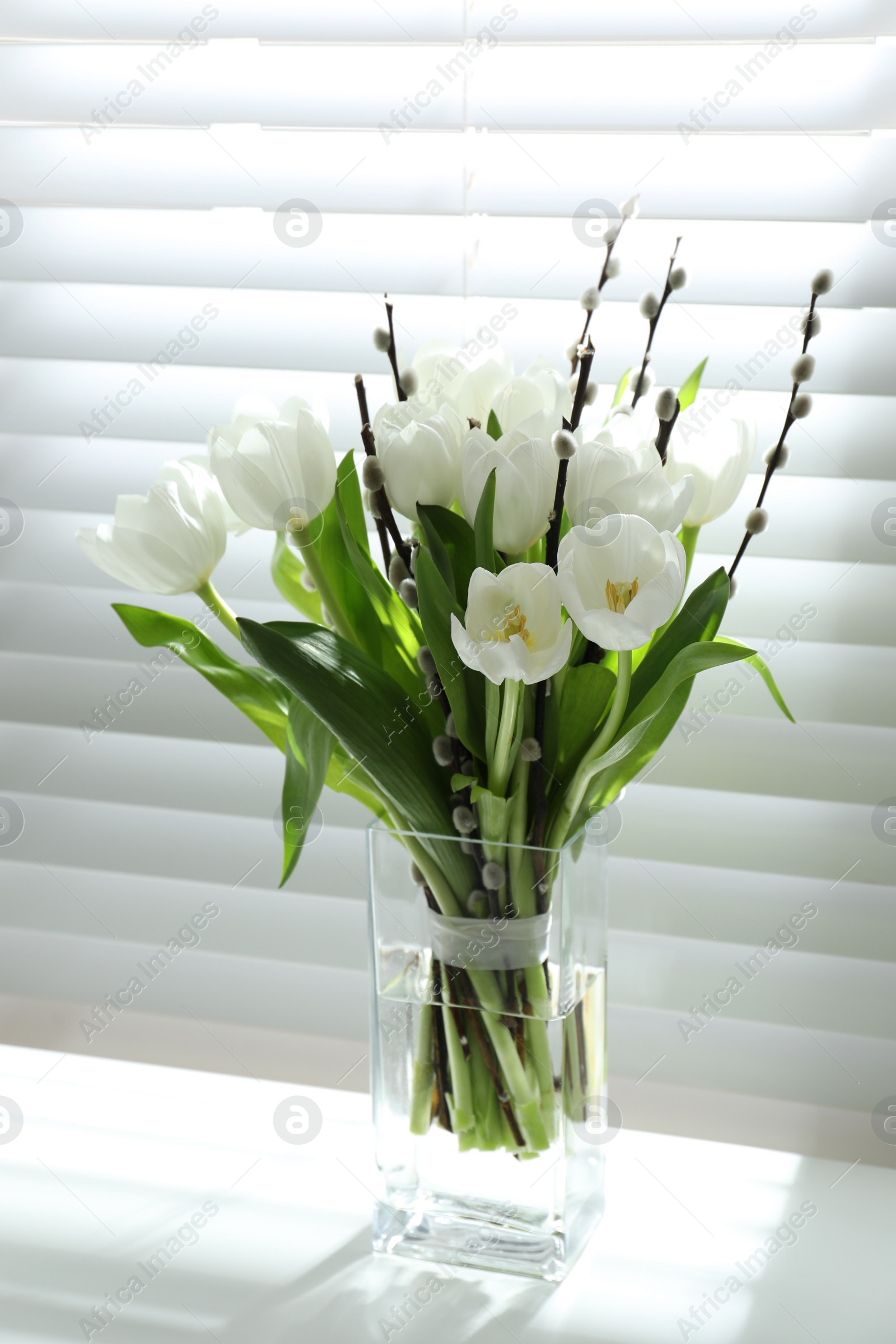 Photo of Beautiful bouquet of willow branches and tulips in vase near window