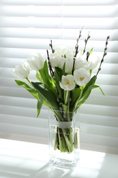 Photo of Beautiful bouquet of willow branches and tulips in vase near window