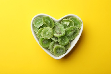 Photo of Bowl with slices of kiwi on color background, top view. Dried fruit as healthy food