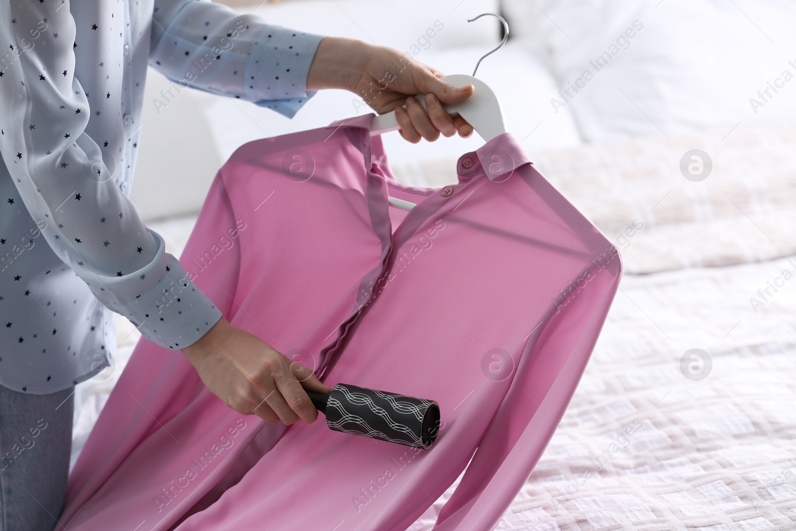 Photo of Young woman cleaning clothes with lint roller at home, closeup