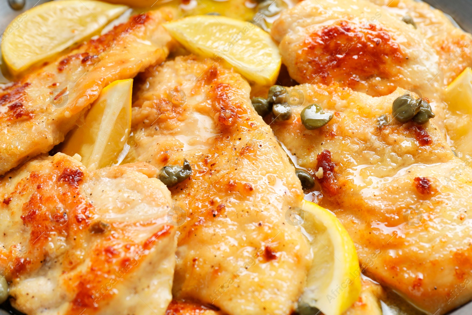 Photo of Delicious chicken piccata with lemons as background, closeup