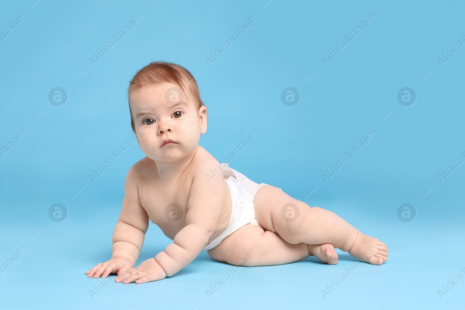 Photo of Cute little baby in diaper on light blue background