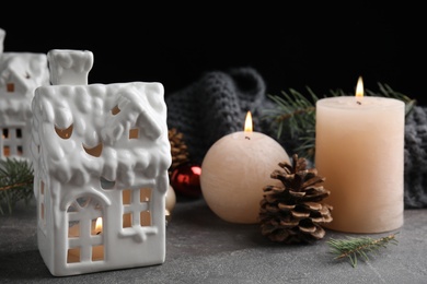 Composition with candle in house shaped holder on grey table. Christmas decoration