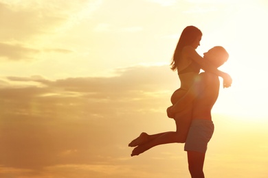 Young woman in bikini spending time with her boyfriend on beach. Lovely couple