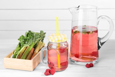 Tasty rhubarb cocktail with raspberry and stalks on white wooden table