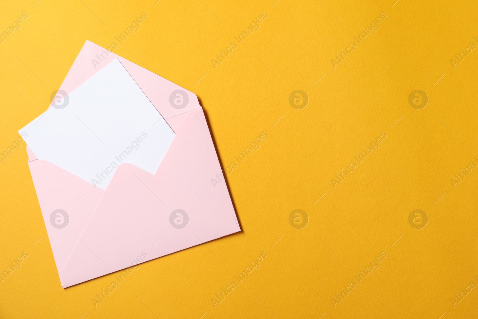 Photo of Blank sheet of paper in open letter envelope on orange background, top view. Space for text